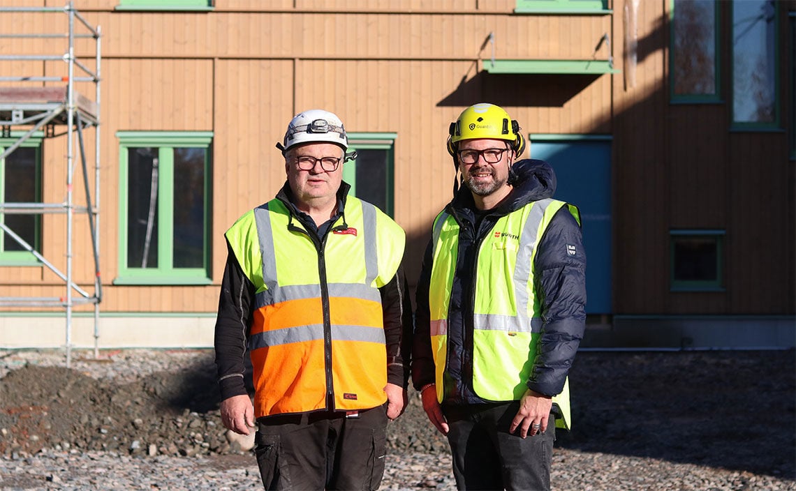 Två män i byggkläder står utanför Tunagården och tittar mot kameran.